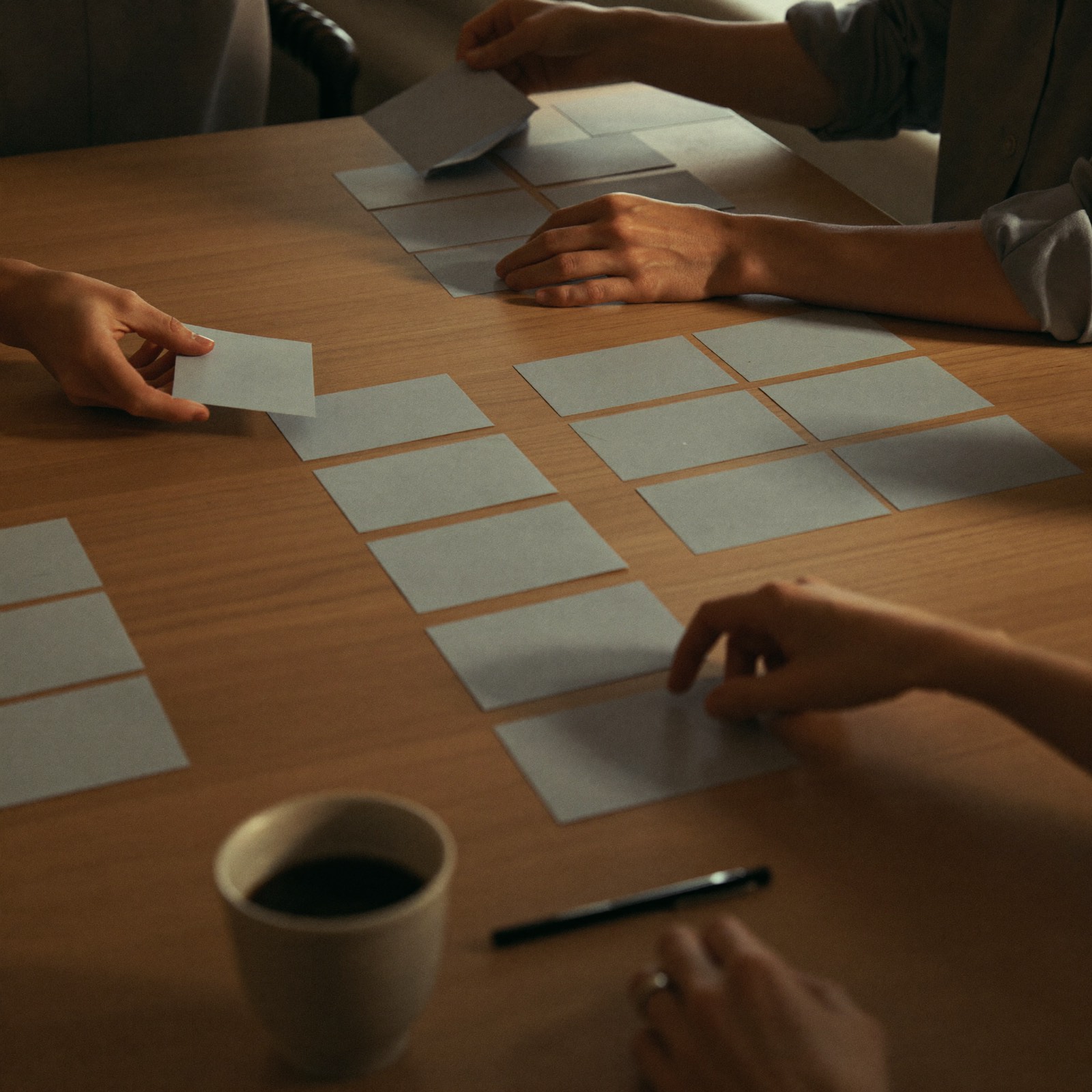 Priorisierung im Workshop: Hände sortieren unbeschriftete Karten auf einem Besprechungstisch in zwei Gruppen